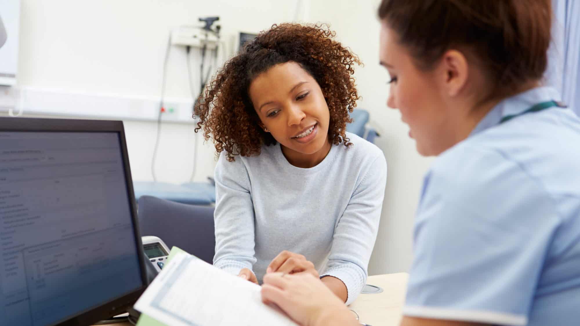 Nurse reviews health history with a patient.