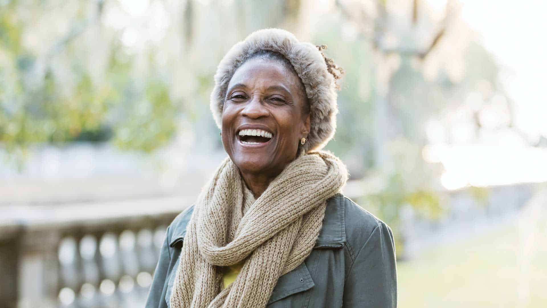 Elderly woman laughing in the park.